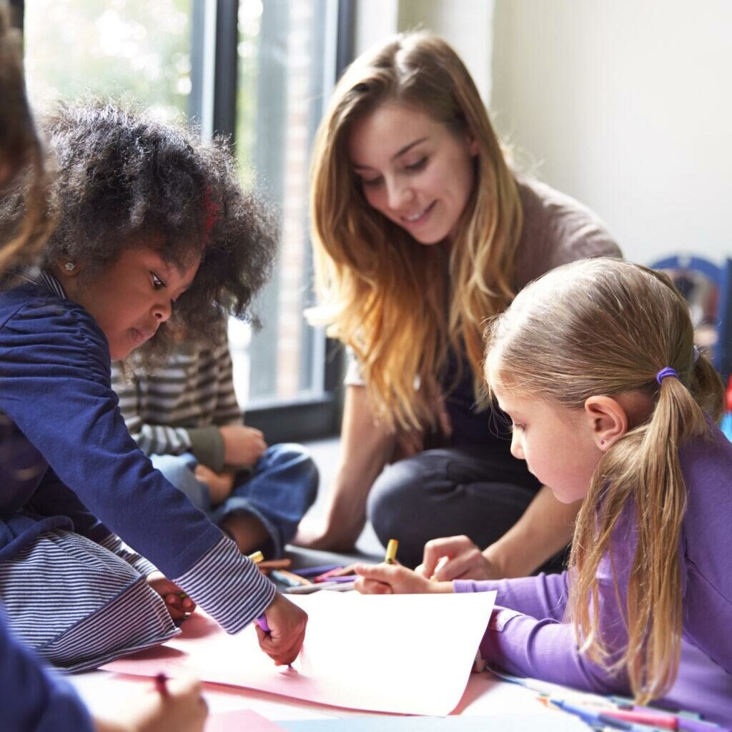 Teacher And Students Drawing On Papers At Child Care